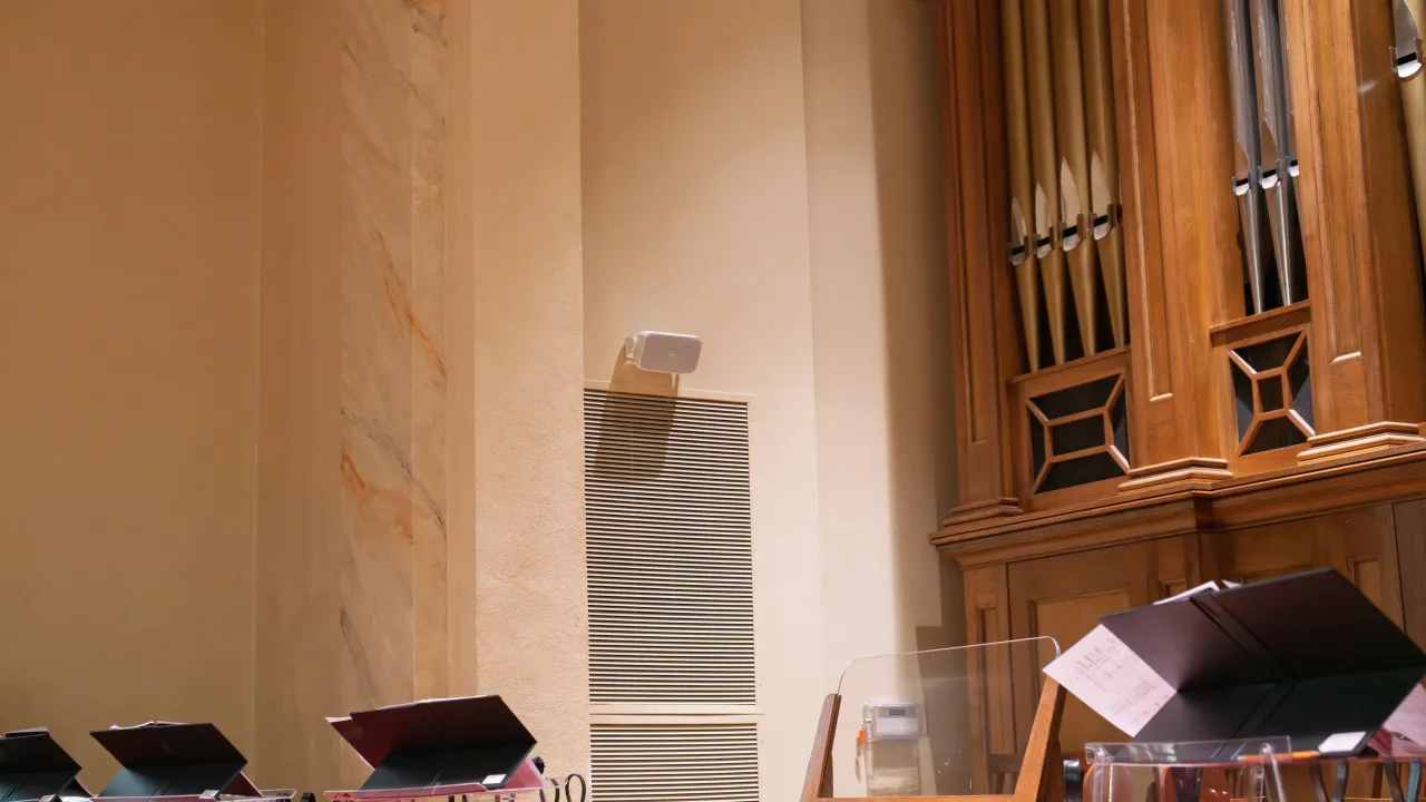 A surface-mount loudspeaker on a column beside the sanctuary pipe organ.