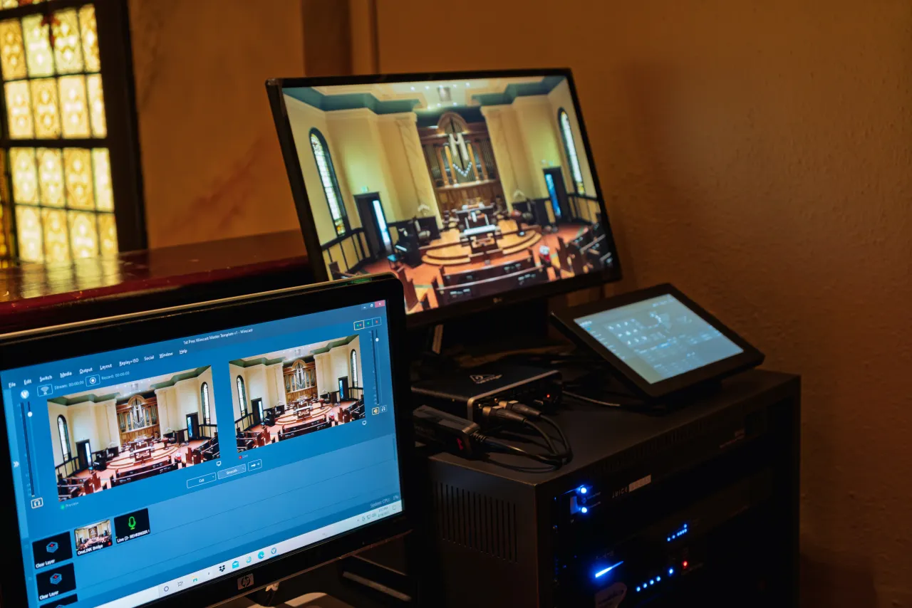 Front-of-house streaming workstation with production monitors, a control tablet, and a PC showing the sanctuary camera feed.