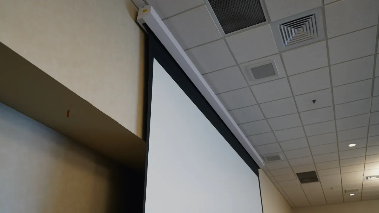 A motorized projection screen lowered beside the ceiling in a Jackson State University event space.