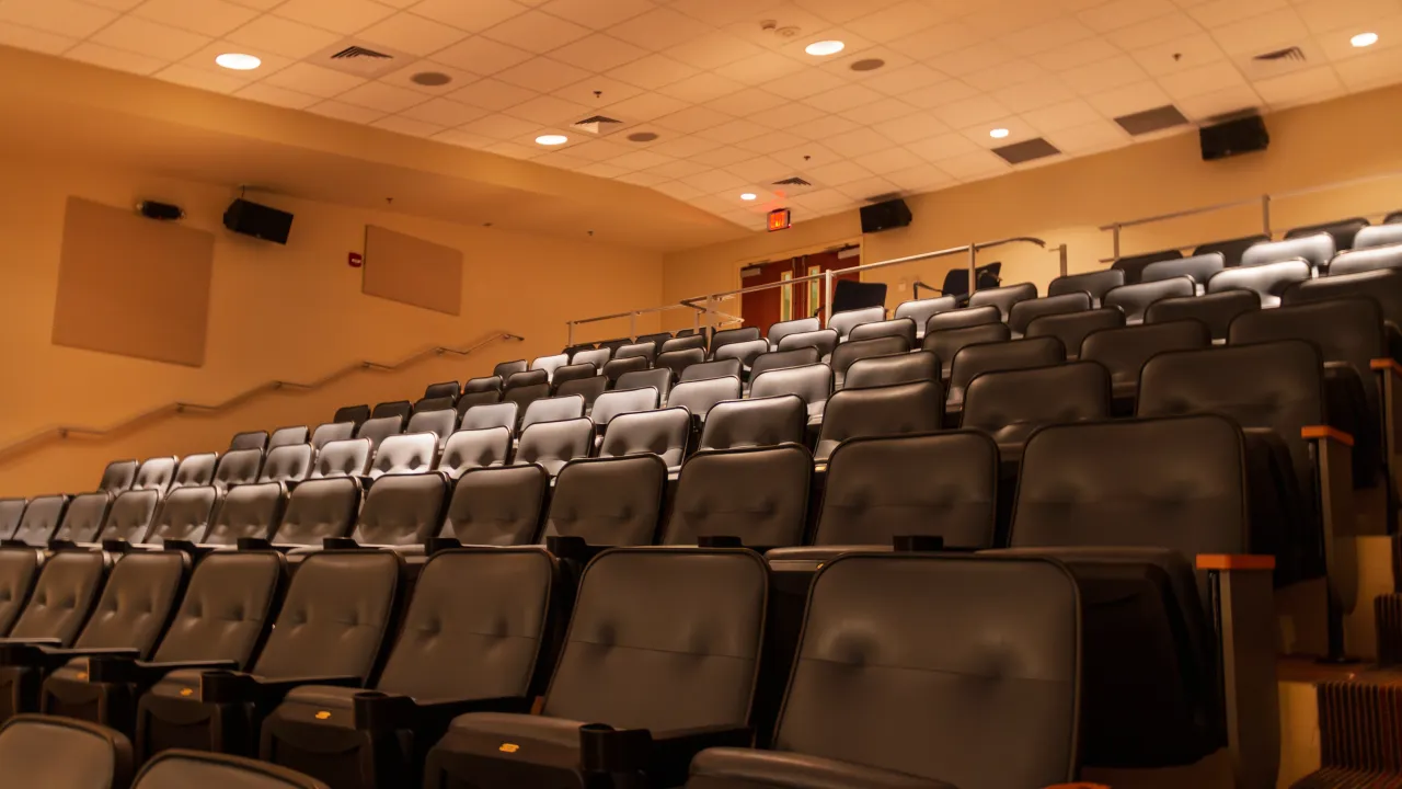 Tiered seating in a Jackson State University lecture hall with wall-mounted loudspeakers.