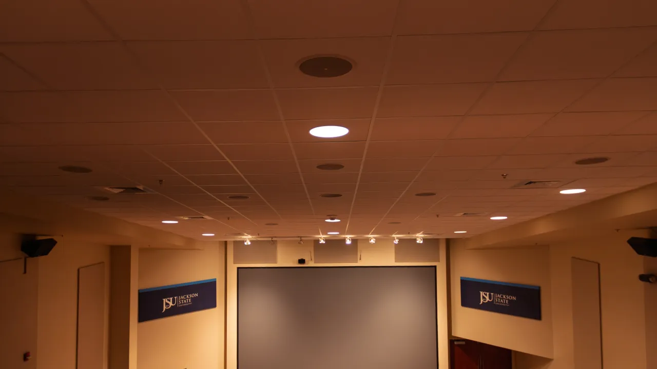 A retractable projection screen flanked by Jackson State University banners in a presentation room.