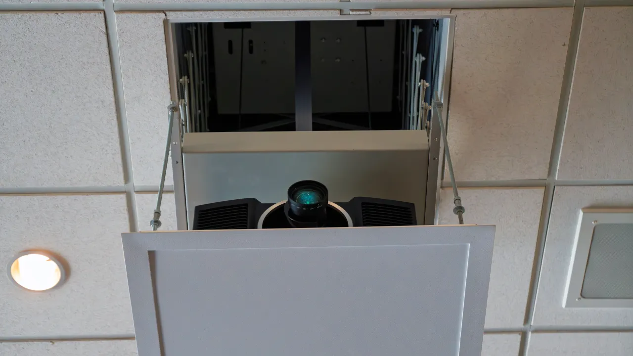 A large-venue projector mounted in a recessed ceiling lift in the Student Center ballroom.