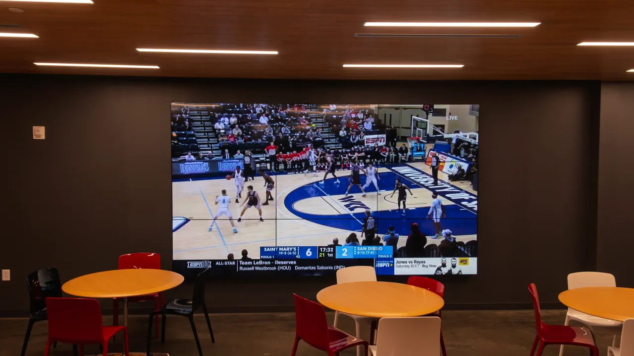 A video wall in the main corridor displaying a live basketball broadcast.