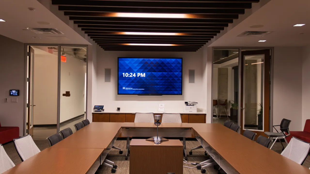 A SESAC boardroom with a wall-mounted display, conference table, and a wood-slat ceiling.