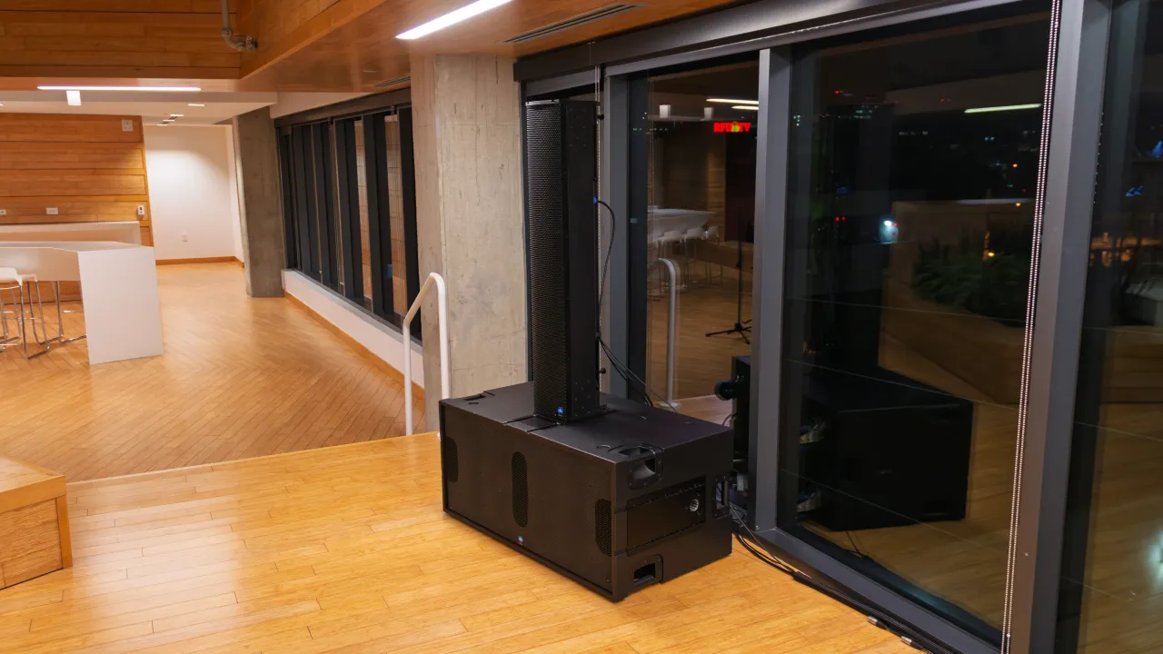 A large loudspeaker cabinet beside floor-to-ceiling glass doors in an open lounge area at SESAC.