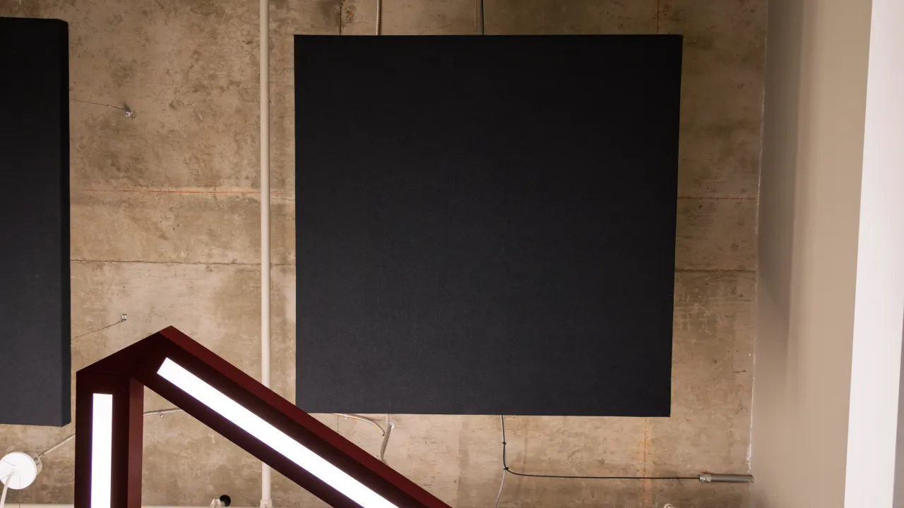 A black acoustic treatment panel mounted on an exposed-concrete wall.