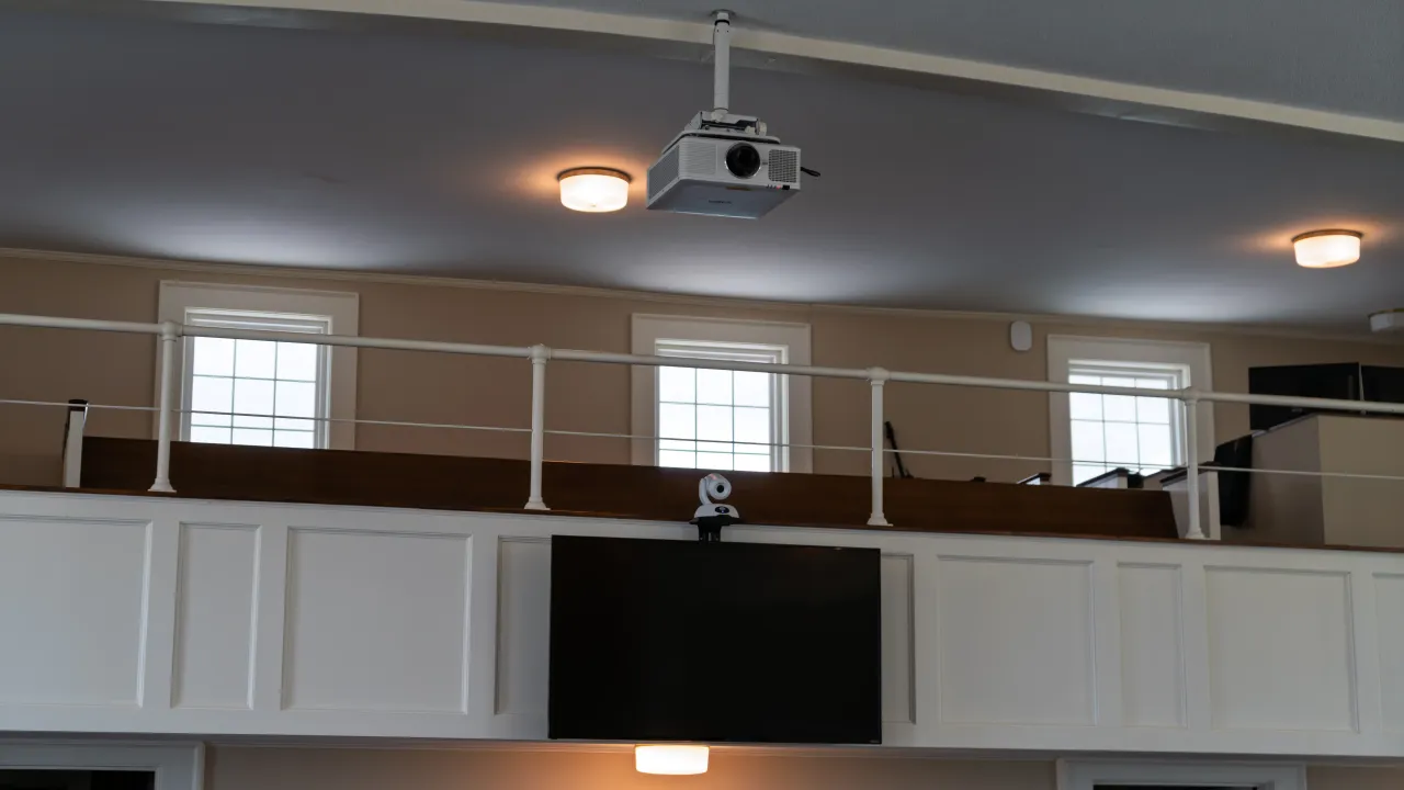 A ceiling-mounted projector, flat-panel display, and camera integrated at the sanctuary balcony.
