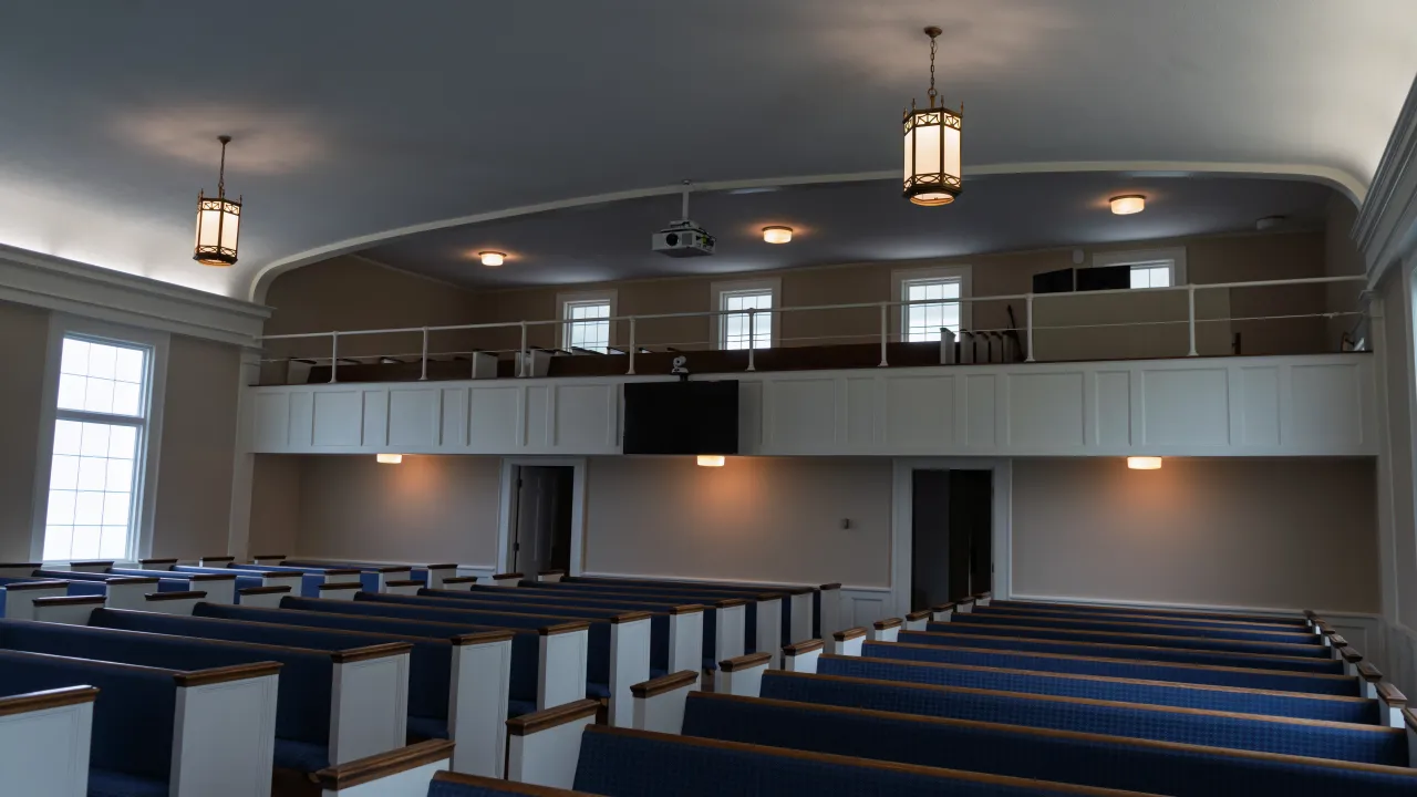 The Sulphur Spring Baptist Church sanctuary seen from the front, with pews, pendant lighting, and a balcony.