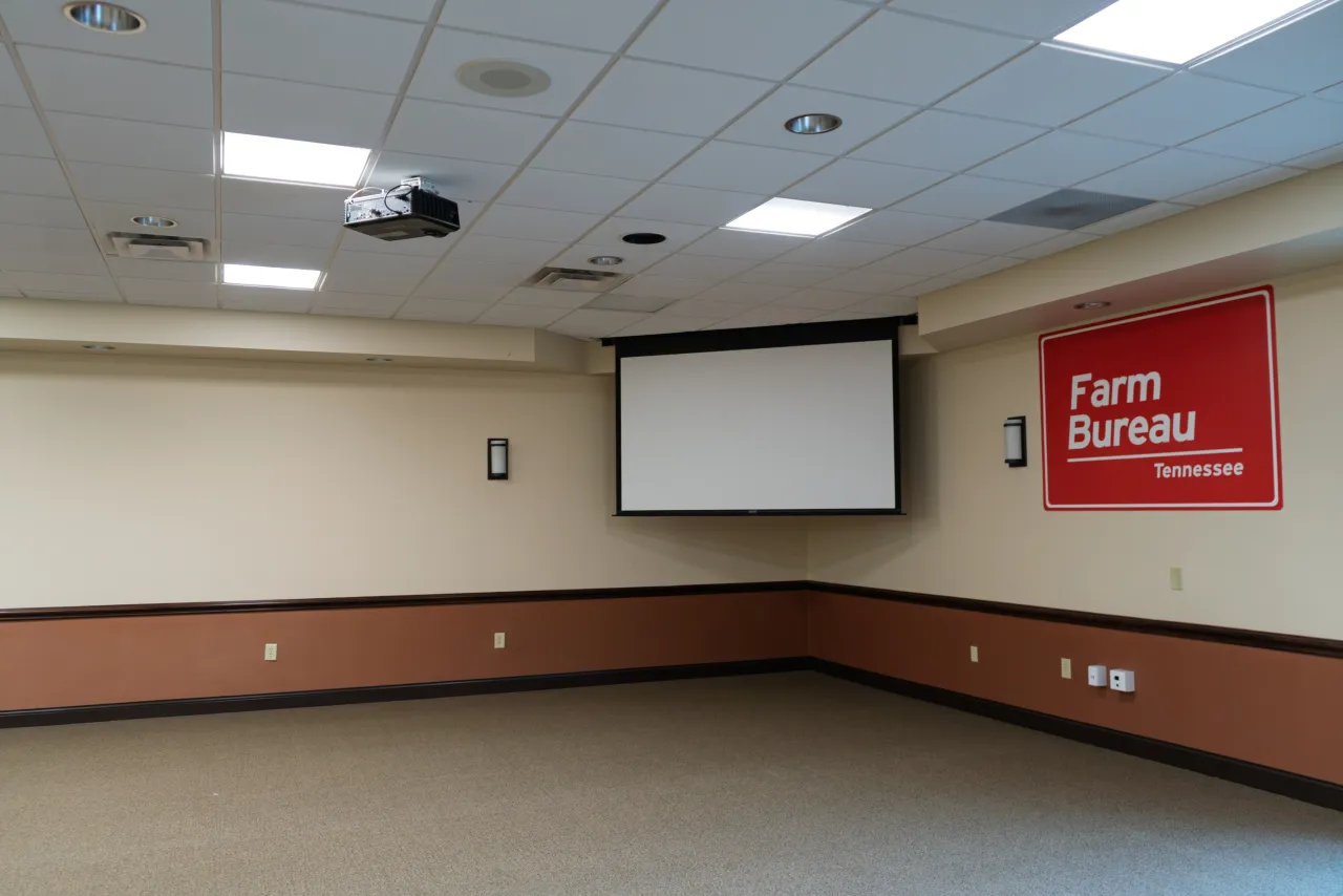 A Tennessee Farm Bureau meeting room with a retractable projection screen, ceiling projector, and the Farm Bureau logo on the wall.