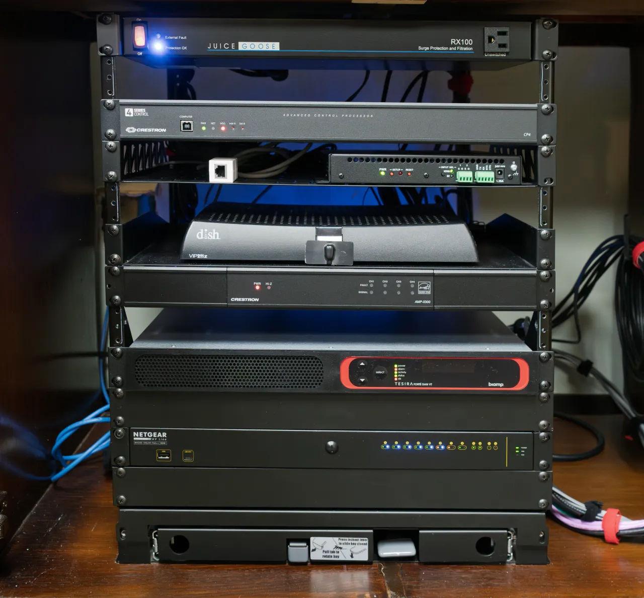Close-up of an AV equipment rack with control processor, amplifier, and network switch.