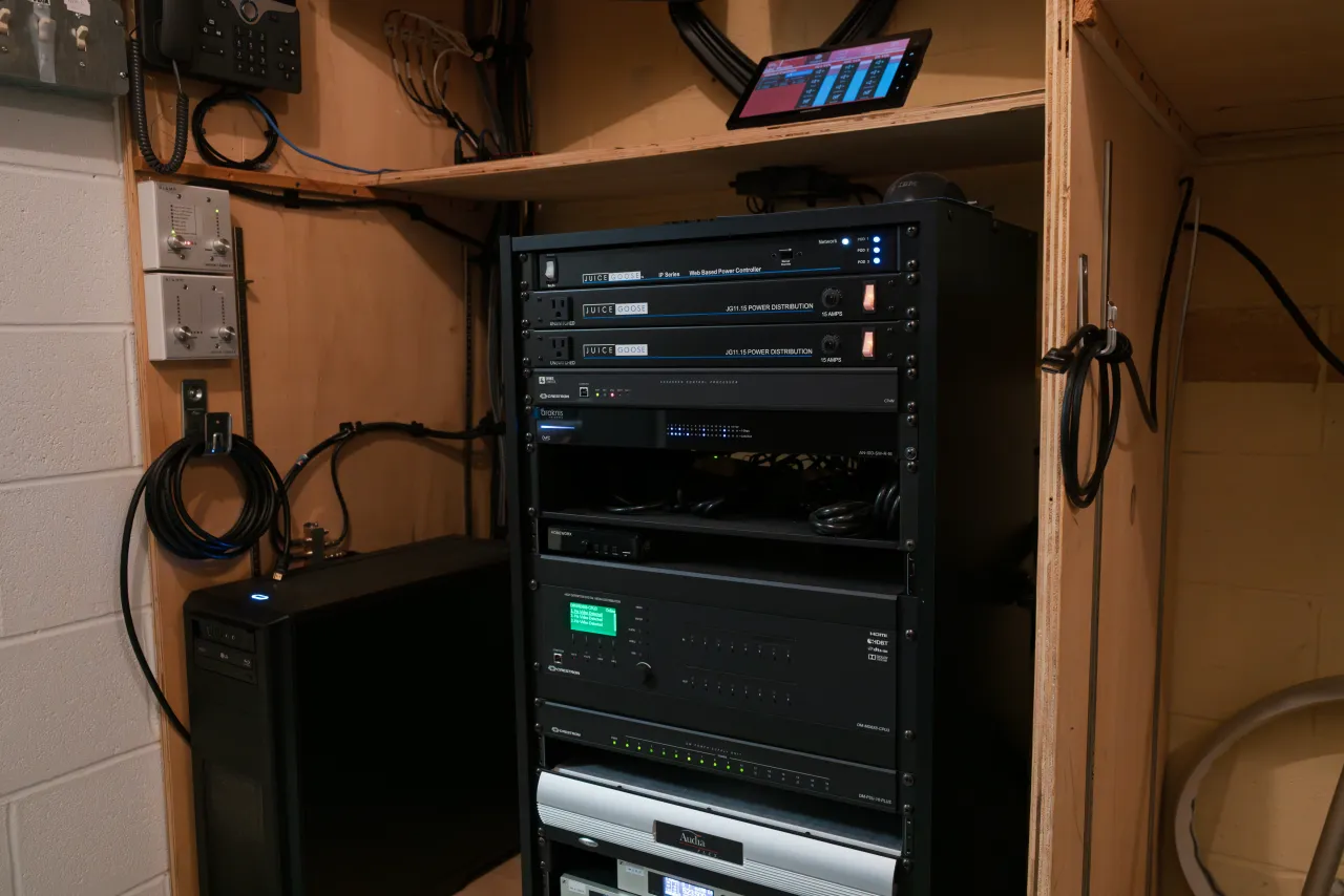 An AV equipment rack with a control panel mounted in a back-of-house closet.
