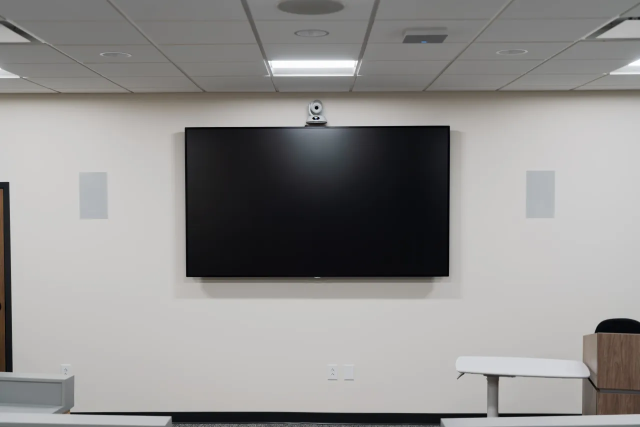 A Tennessee Farm Bureau training room with tiered desks, ceiling loudspeakers, and a window to the control room.