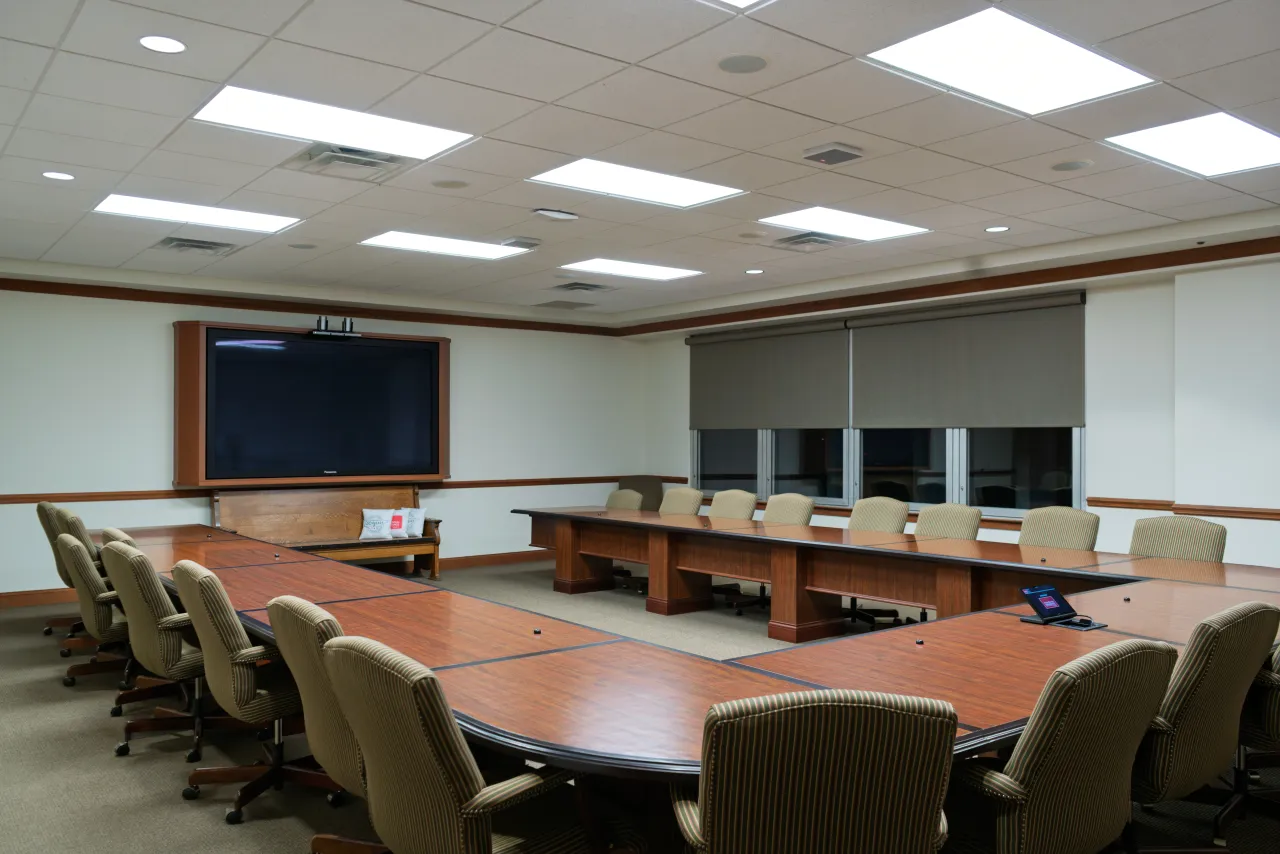 The executive boardroom with a large conference table, wall-mounted display, and ceiling microphones.
